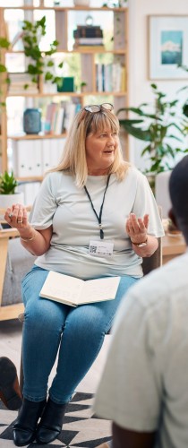 Woman gesturing while speaking during professional consultation in bright office with bookshelf and plants