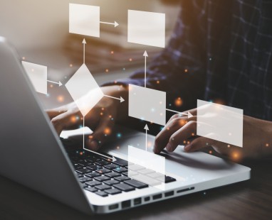 Person typing on laptop with digital workflow visualization overlay showing connected blank panels with directional arrows, representing data or information flow.
