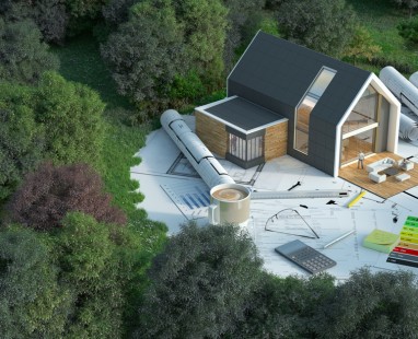 Architectural model house on blueprints with design tools, calculator and energy efficiency chart, surrounded by green landscape. 