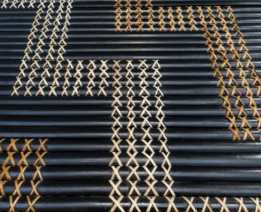 Traditional Māori tukutuku panel showing intricate cross-weave patterns in natural fibers, with geometric designs created against dark background rods.