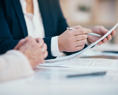 Professional in navy suit reviewing documents with silver pen, displaying focused attention to detail