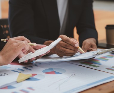 Business professionals analysing financial data charts and graphs with calculator