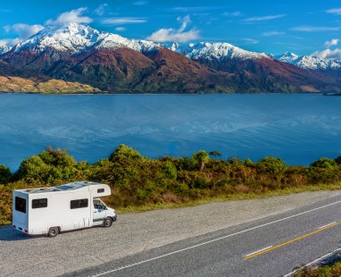 Campervan parked on roadside overlooking lake and snow-capped mountains in Queenstown New Zealand 