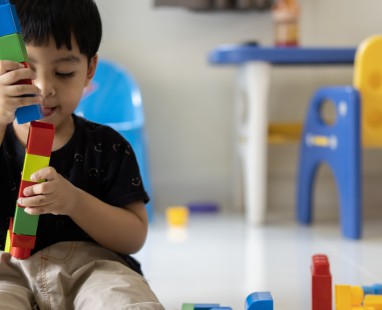 Young boy playing with colourful stacking toys