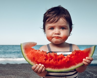 Child eating watermelon slice at beach