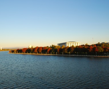 Lake Burley Griffin with autumn trees and National Library at sunset