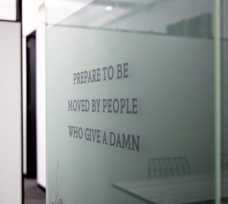 Frosted glass panel with Allen + Clarke's core value statement: "PREPARE TO BE MOVED BY PEOPLE WHO GIVE A DAMN". 