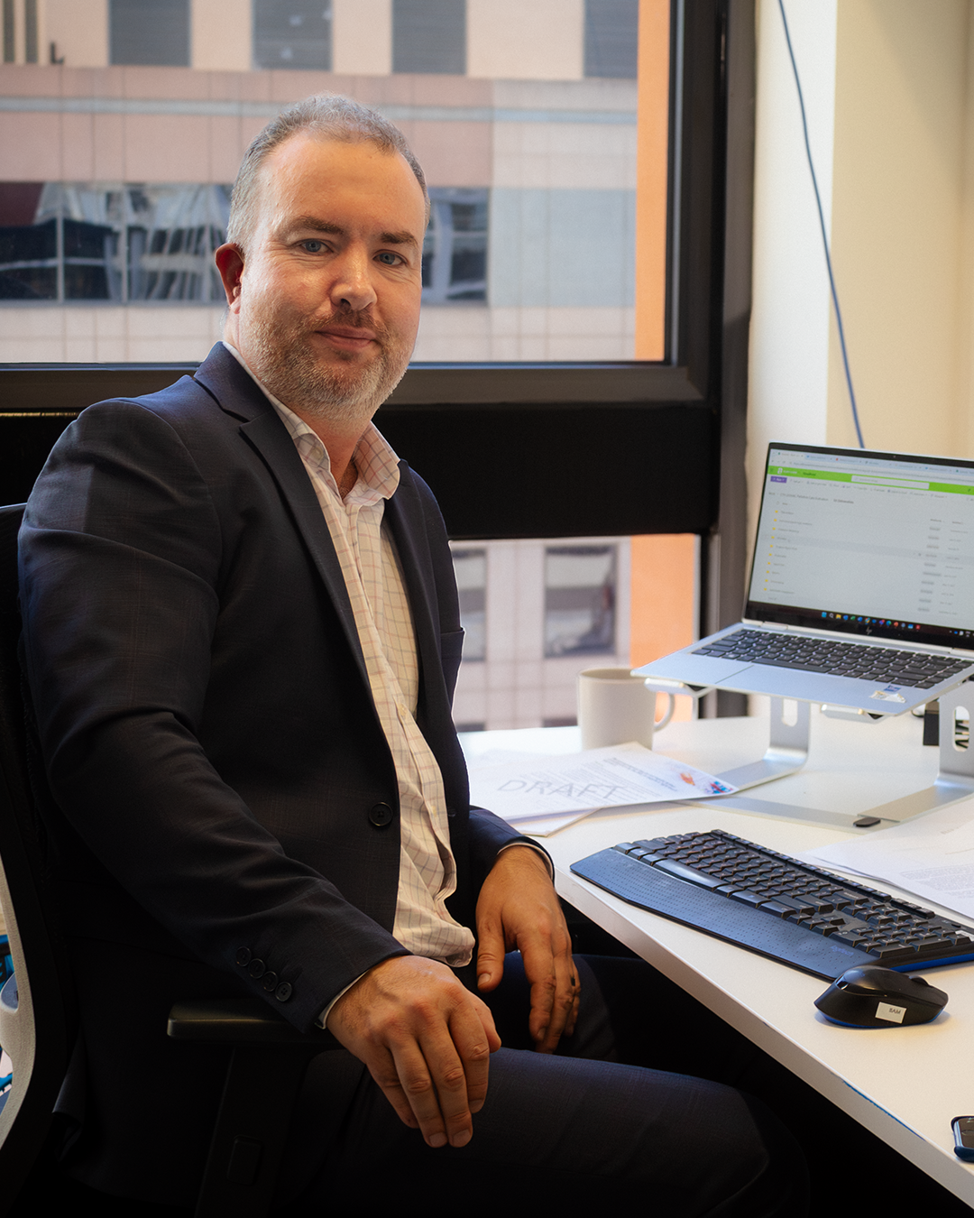 Professional at desk with laptop in modern office with city views