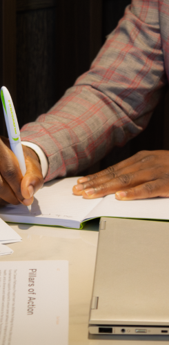 Close-up of hand writing notes on document, capturing key information during consultation process.