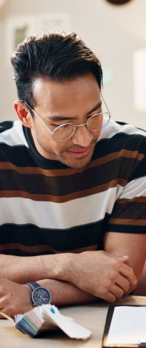 Team member with glasses in striped shirt focused on reviewing documents, embodying careful attention to project details.