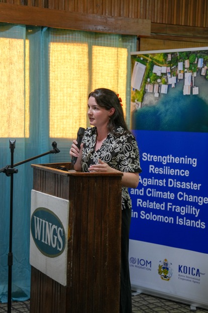Speaker at podium presenting climate resilience initiative for Solomon Islands, showcasing international development partnerships.