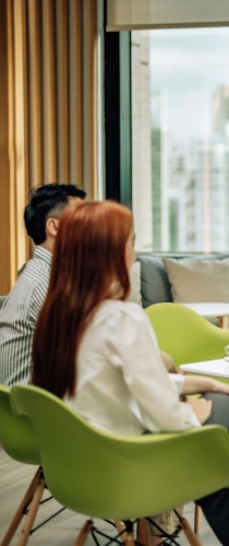 Partners in consultation at bright meeting space with contemporary green seating, focused on discussion in comfortable environment.