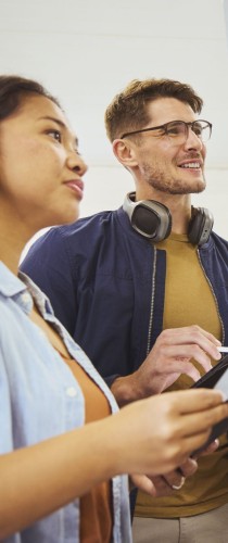 Smiling team members collaborating with mobile technology and notes, displaying engaged interaction and positive working relationship.