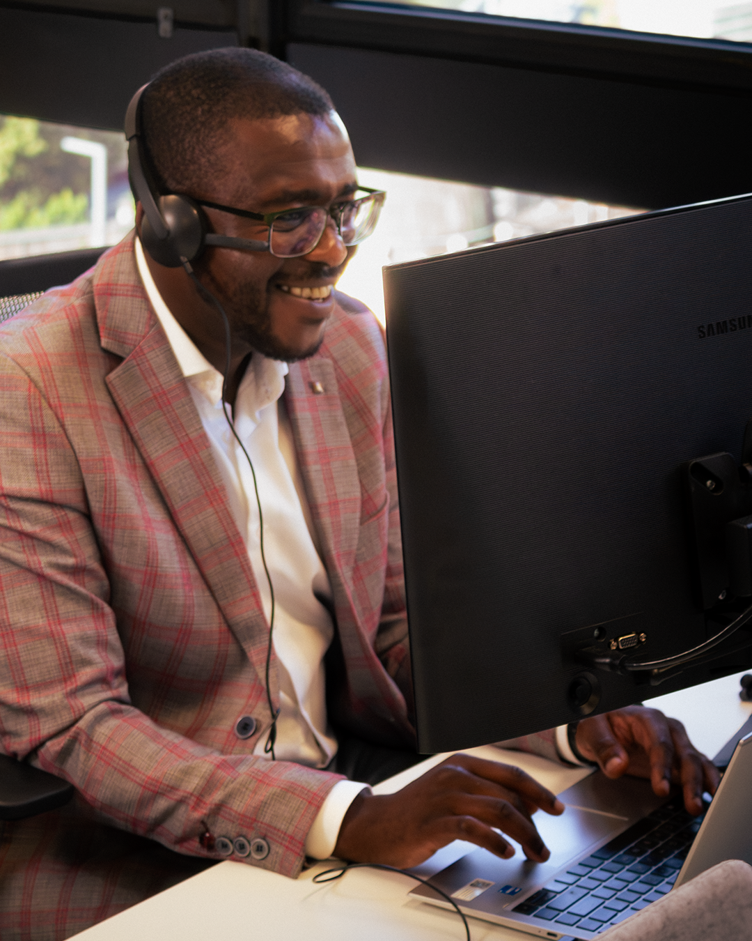 Smiling professional with headset providing customer support at computer workstation