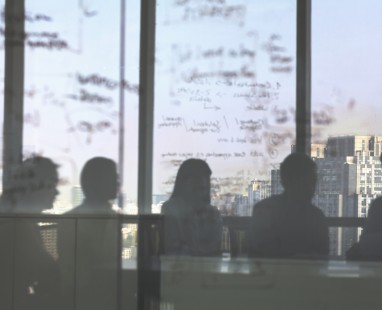 Silhouettes of people in meeting room against bright window backdrop