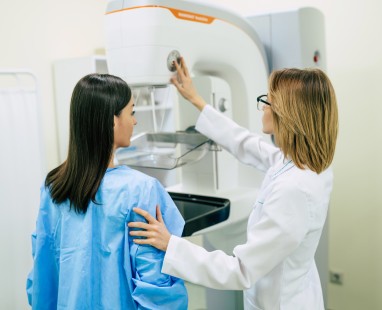 Healthcare worker positioning patient for mammogram screening