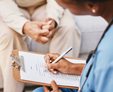 Medical professional writing notes on clipboard during consultation