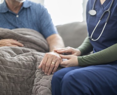Healthcare provider offering supportive hand hold to patient