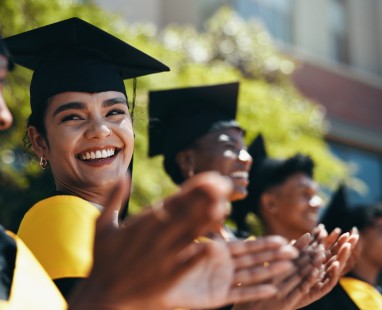 Graduate smiling and applauding at university graduation ceremony