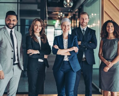 Five business professionals standing confidently together in modern office corridor